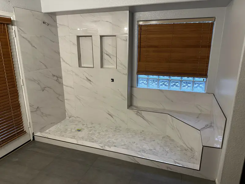 Custom marble-look shower tile with bench and niches