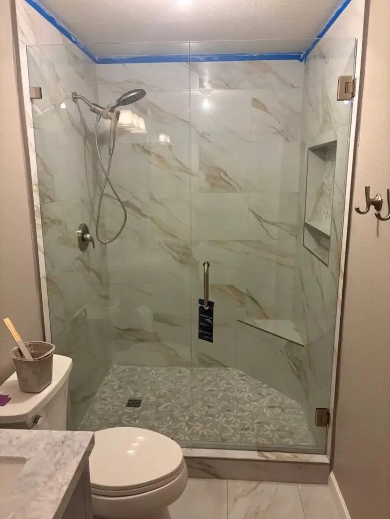 Glass shower enclosure with marble-look tile and mosaic shower floor
